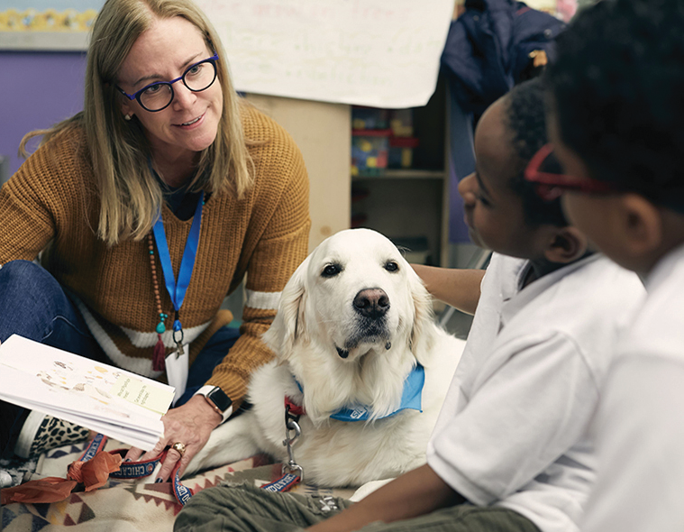 Rebecca Cline reading with students and a very cute white dog