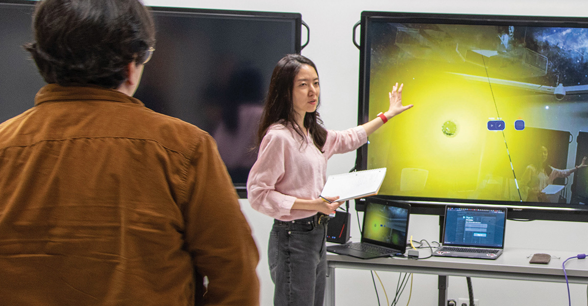 Woman standing in front of monitor gesturing